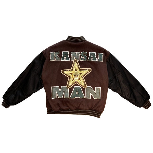 Kansai Man label 1980’s varsity jacket with black leather sleeves and brown wool body, leather accent slash pockets, rib knit collar, cuffs and bottom hem, logo front snap buttons. Super Stars varsity front appliqué lettering, Kansai Man in back with centre star. Full quilted lining, 2 inside slash pockets. Made in Japan 