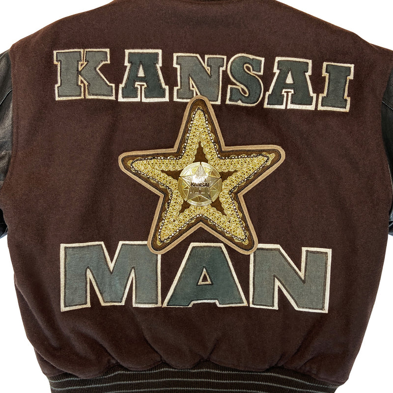 Kansai Man label 1980’s varsity jacket with black leather sleeves and brown wool body, leather accent slash pockets, rib knit collar, cuffs and bottom hem, logo front snap buttons. Super Stars varsity front appliqué lettering, Kansai Man in back with centre star. Full quilted lining, 2 inside slash pockets. Made in Japan 