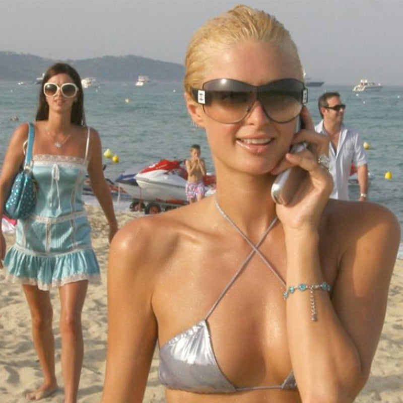 Paris Hilton wearing Chanel Oversized Shield Sunglassesk.  Oversized lens oversized lens surrounded by  metal frame, wide arms, square CC silver logo at sides that wrap on to the lens 