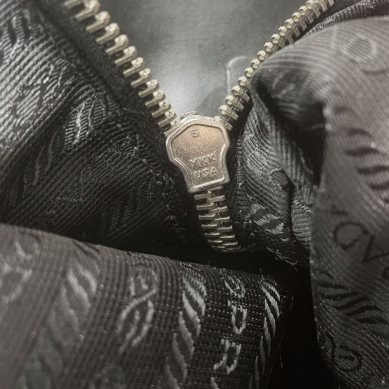 Prada tessuto Shoulder Bag Circa 2000's, black nylon bag with leather handles, front panels and piping, front logo plaque. Zip closure with silver-tone YKK zipper pull opens to black jacquard logo lining, one interior pocket. Made in Italy 