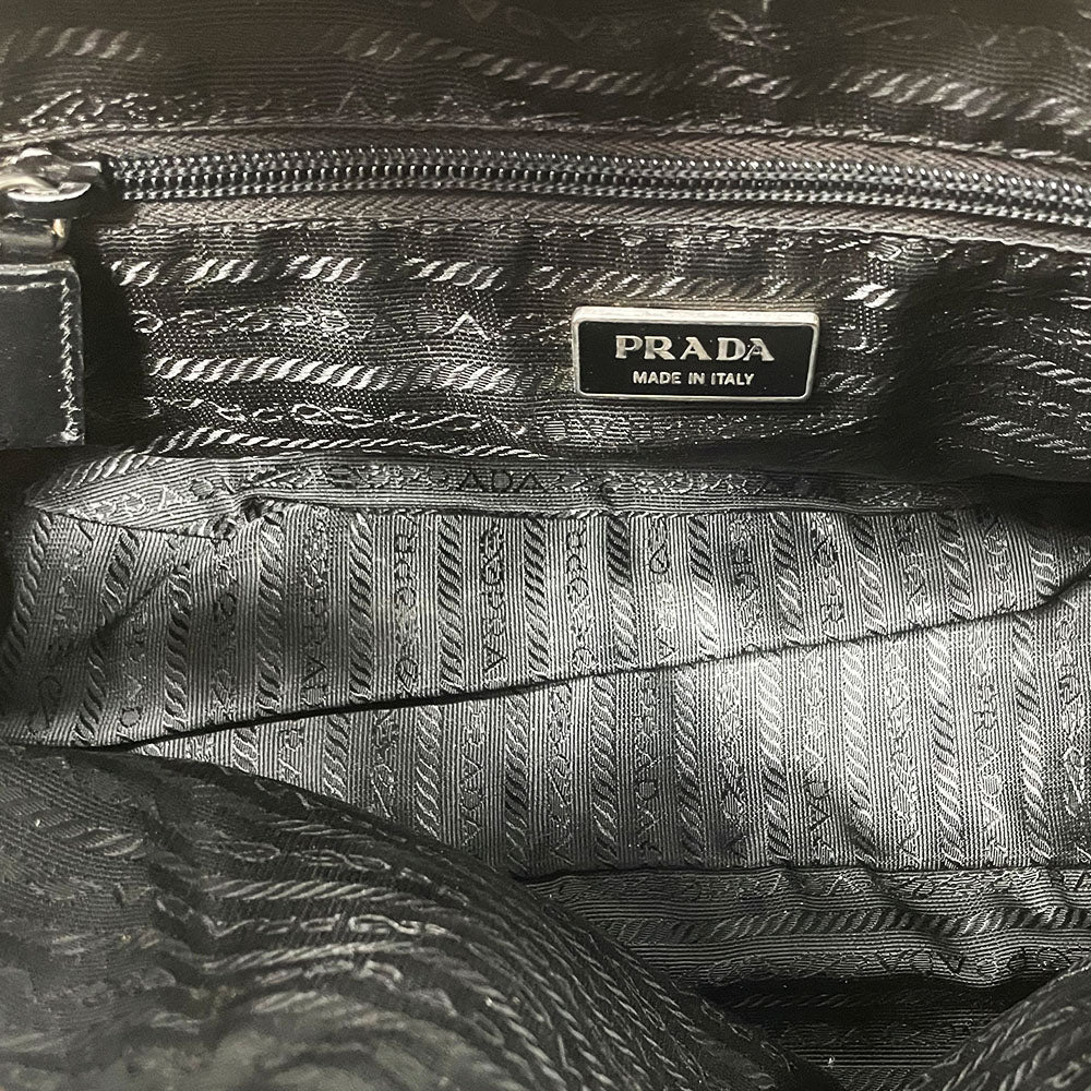 Prada tessuto Shoulder Bag Circa 2000's, black nylon bag with leather handles, front panels and piping, front logo plaque. Zip closure with silver-tone YKK zipper pull opens to black jacquard logo lining, one interior pocket. Made in Italy 