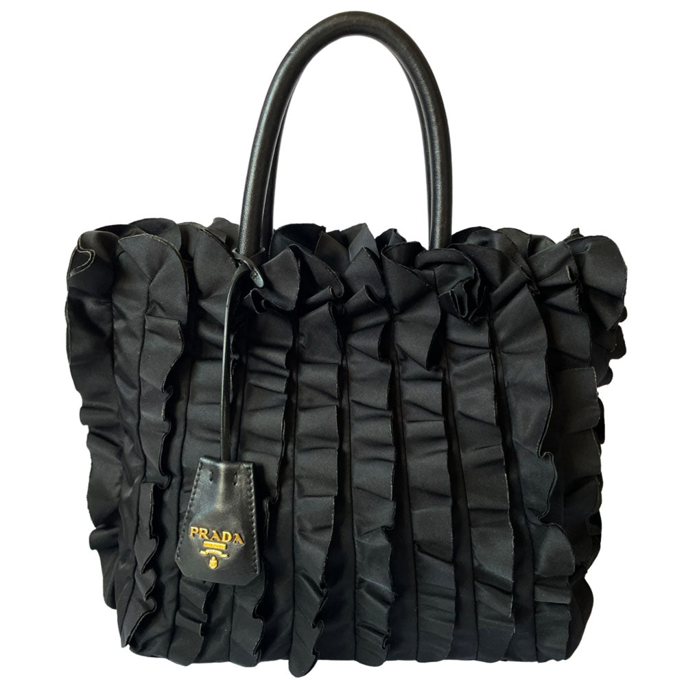 Prada 2000s black ruffled body tessuto nylon tote with leather handles, accent and hanging clochette key holder featuring gold-tone logo. Gold-tone hardware, interior logo, zippers and logo engraved feet. Magnetic snap closure, interior trademark leather label, 2 interior zip pockets, Prada logo lining. Made in Italy 