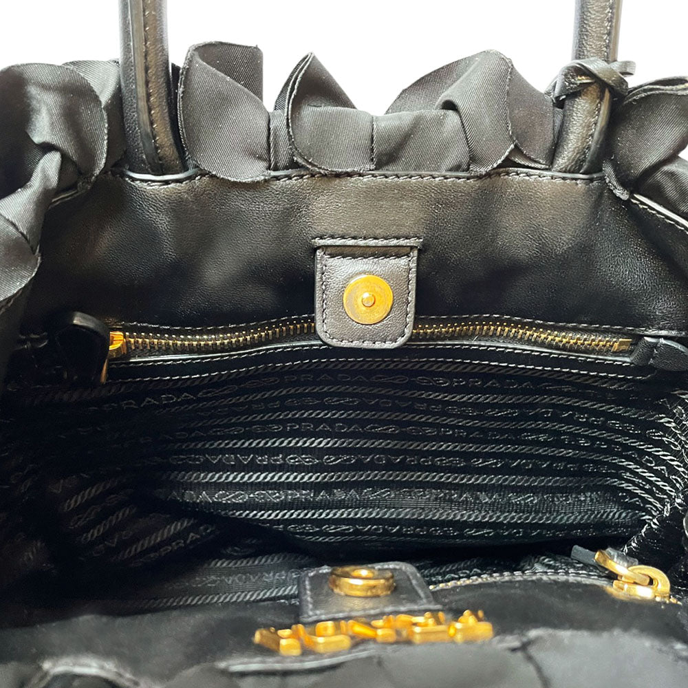 Prada 2000s black ruffled body tessuto nylon tote with leather handles, accent and hanging clochette key holder featuring gold-tone logo. Gold-tone hardware, interior logo, zippers and logo engraved feet. Magnetic snap closure, interior trademark leather label, 2 interior zip pockets, Prada logo lining. Made in Italy 