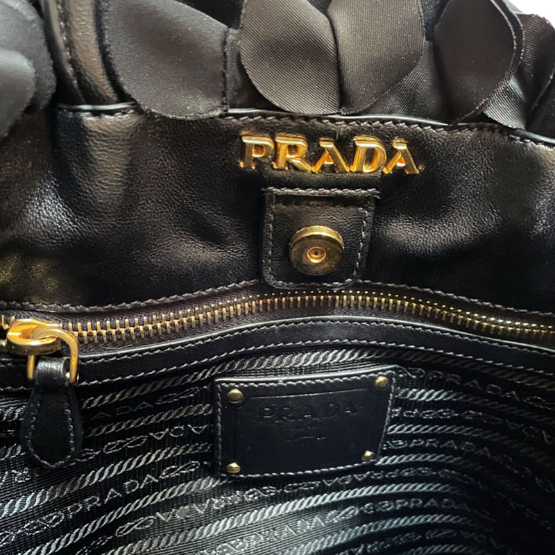 Prada 2000s black ruffled body tessuto nylon tote with leather handles, accent and hanging clochette key holder featuring gold-tone logo. Gold-tone hardware, interior logo, zippers and logo engraved feet. Magnetic snap closure, interior trademark leather label, 2 interior zip pockets, Prada logo lining. Made in Italy 