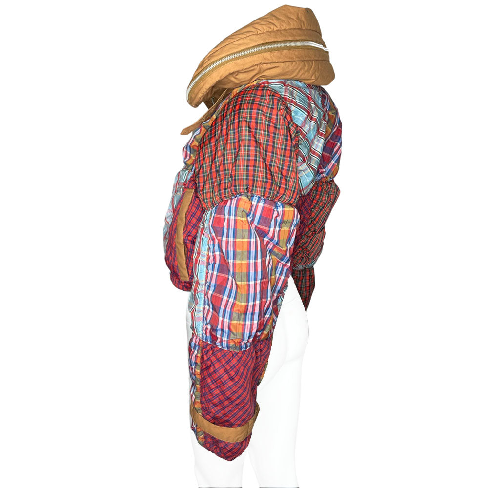 Tsumori Chisato long sleeved patchwork reversible hooded puffer jacket featuring a mix of madras & tartan fabrics with brown leather & canvas accent straps at wrists and pockets. Front zip closure with button, drawstring at waistline, puffy collar zips open to reveal hood. Reversible to all brown with zip-in tartan hood. Made in Japan 