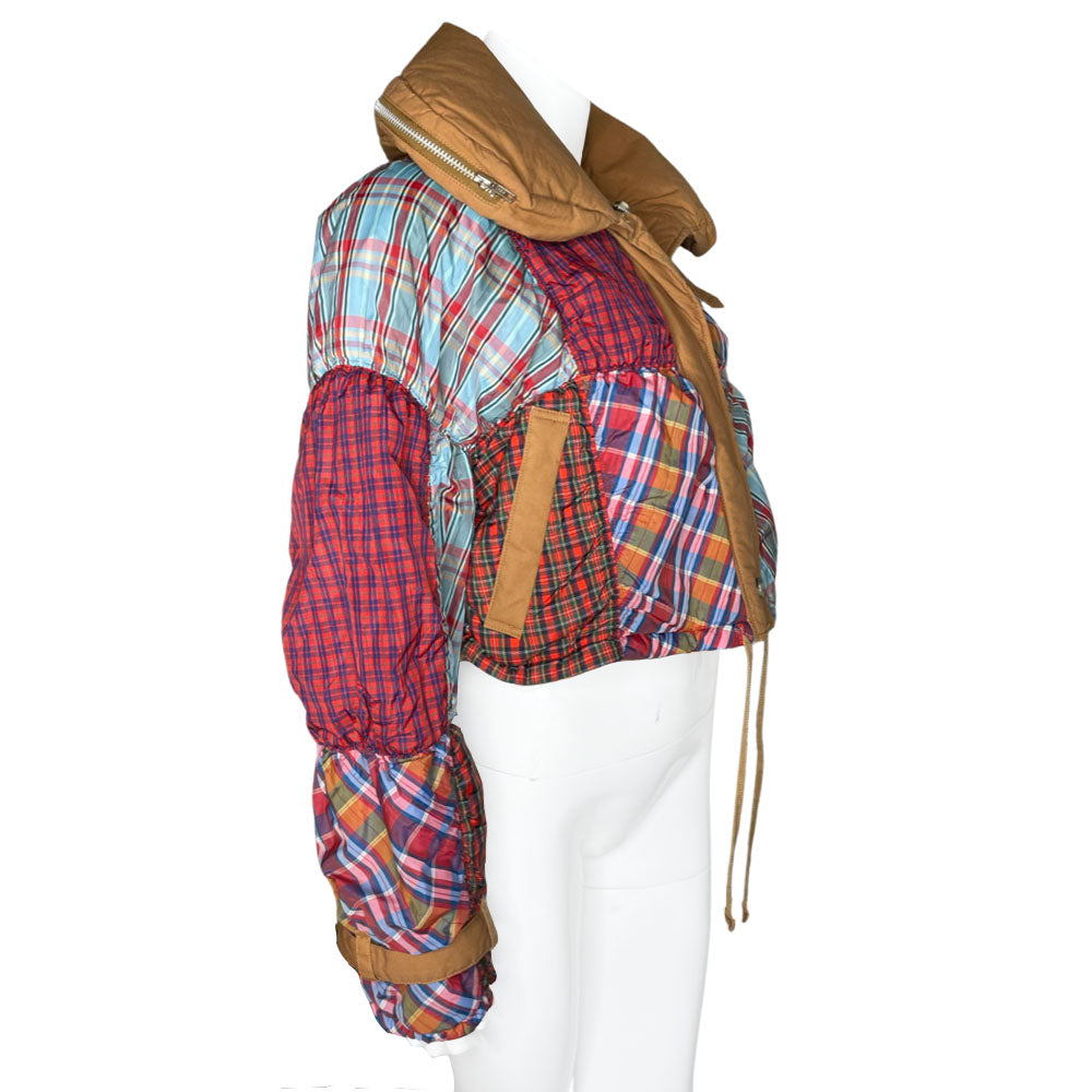 Tsumori Chisato long sleeved patchwork reversible hooded puffer jacket featuring a mix of madras & tartan fabrics with brown leather & canvas accent straps at wrists and pockets. Front zip closure with button, drawstring at waistline, puffy collar zips open to reveal hood. Reversible to all brown with zip-in tartan hood. Made in Japan 