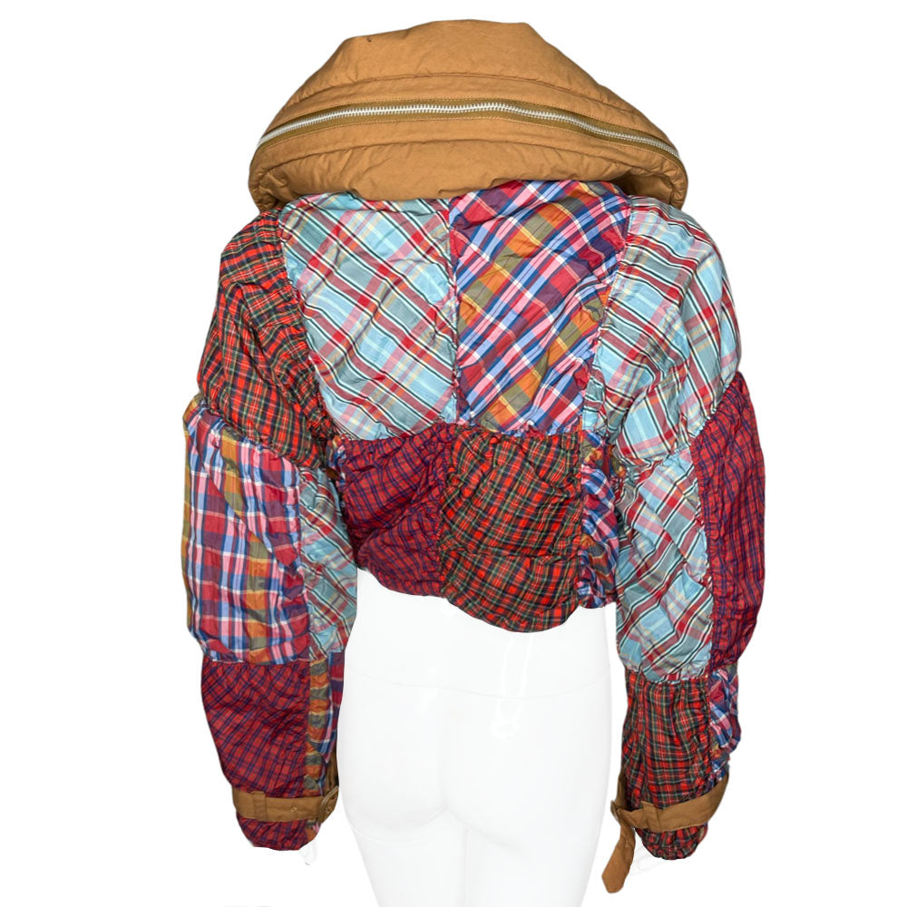 Tsumori Chisato long sleeved patchwork reversible hooded puffer jacket featuring a mix of madras & tartan fabrics with brown leather & canvas accent straps at wrists and pockets. Front zip closure with button, drawstring at waistline, puffy collar zips open to reveal hood. Reversible to all brown with zip-in tartan hood. Made in Japan 